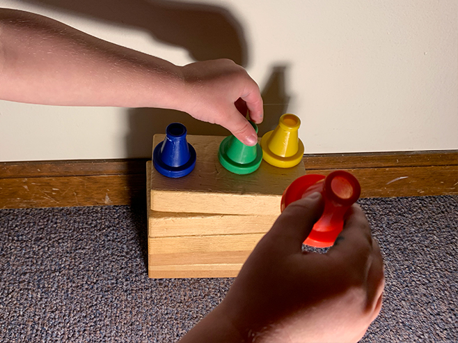 Light shining on student stacking items on a stack of blocks.