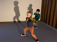 Light shining on two students posing and their shadows.